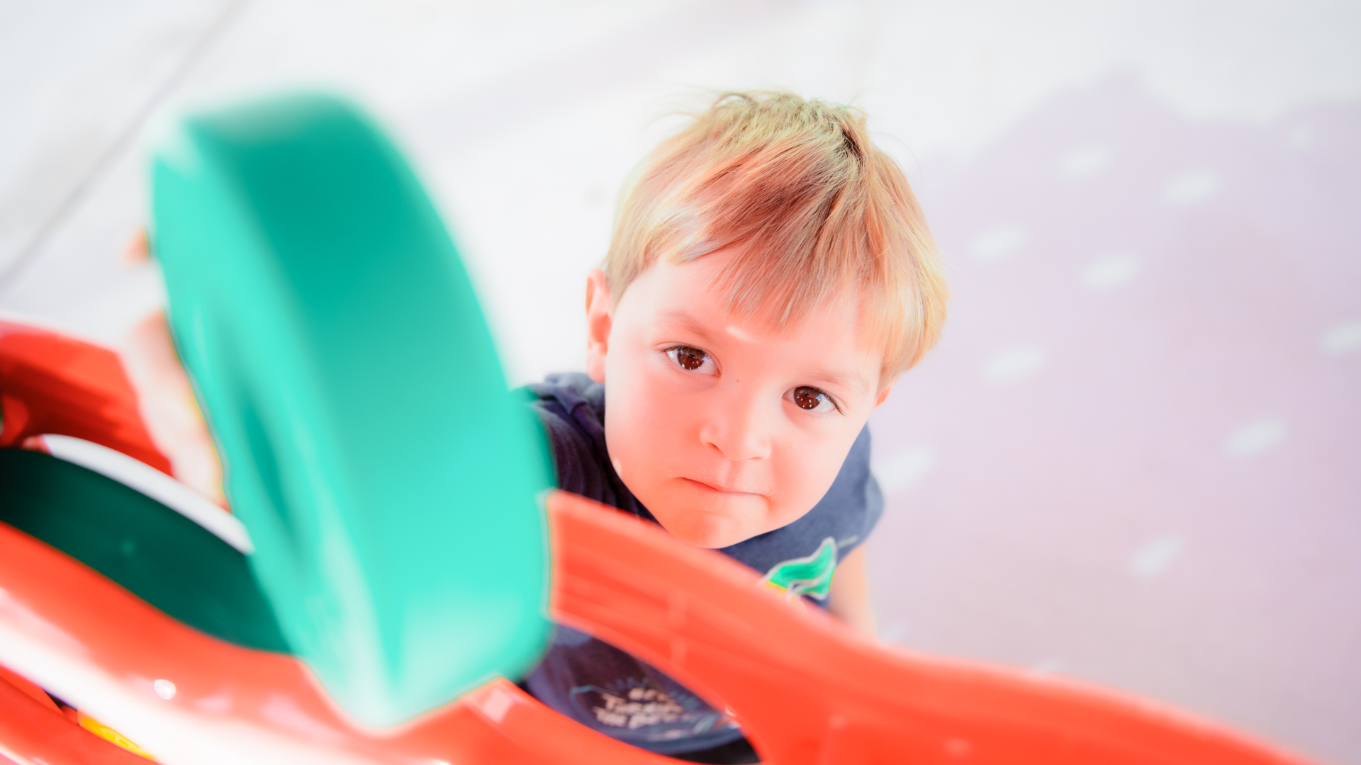 A young boy with a determined facial expression reaches with a circular block toy